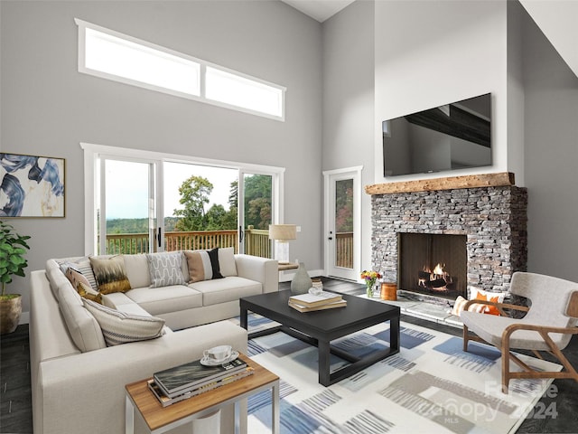 living room with wood-type flooring, a towering ceiling, and a stone fireplace