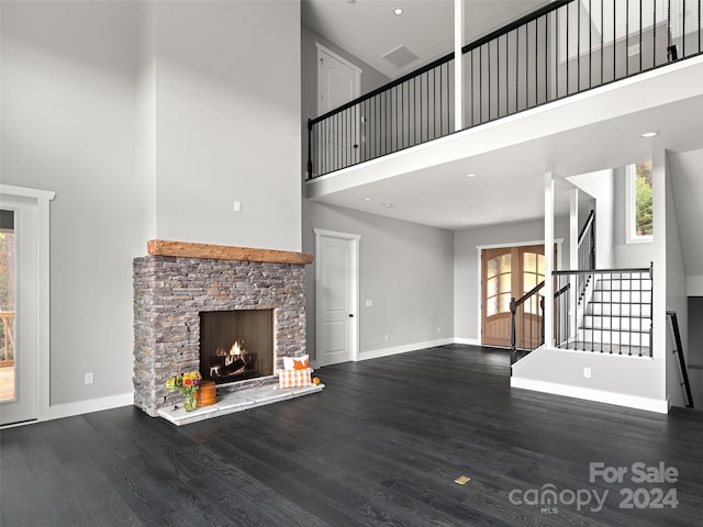 unfurnished living room with a fireplace, wood-type flooring, and a high ceiling