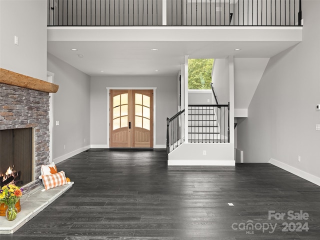 unfurnished living room with a healthy amount of sunlight, a fireplace, a high ceiling, and dark wood-type flooring