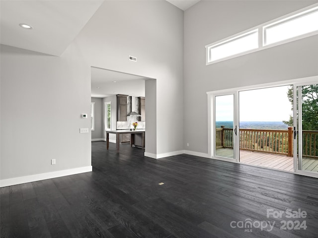 unfurnished living room featuring dark hardwood / wood-style flooring and a towering ceiling