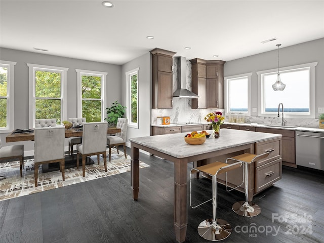 kitchen with tasteful backsplash, wall chimney exhaust hood, sink, pendant lighting, and dishwasher