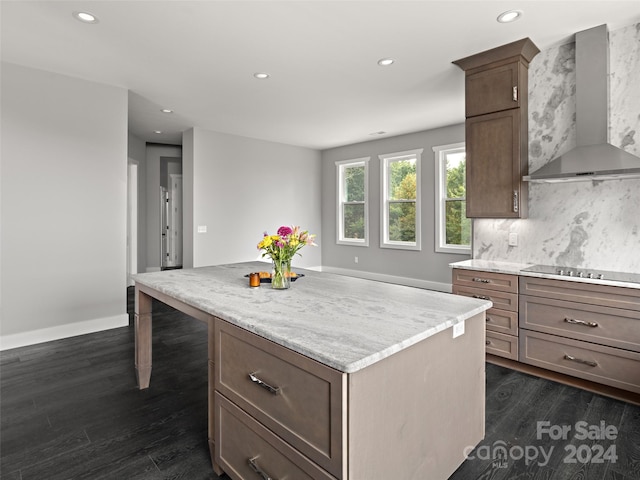 kitchen with dark wood-type flooring, wall chimney exhaust hood, black electric cooktop, tasteful backsplash, and a kitchen island