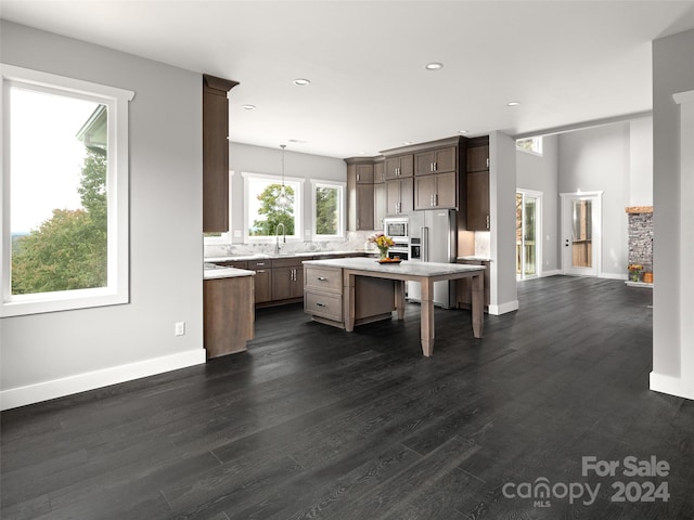 kitchen featuring sink, hanging light fixtures, dark wood-type flooring, a kitchen island, and appliances with stainless steel finishes