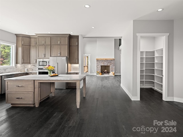 kitchen featuring a fireplace, dark hardwood / wood-style flooring, a kitchen island, and appliances with stainless steel finishes