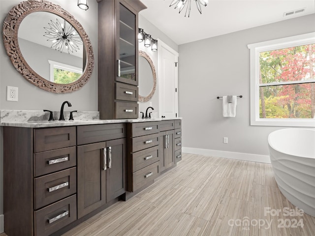 bathroom featuring a chandelier, hardwood / wood-style floors, vanity, and a bathtub