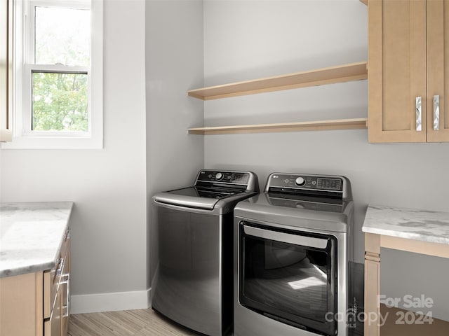 laundry room with washer and dryer, light hardwood / wood-style floors, and cabinets