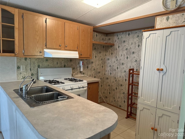 kitchen with a textured ceiling, light tile patterned floors, vaulted ceiling, sink, and white gas stove