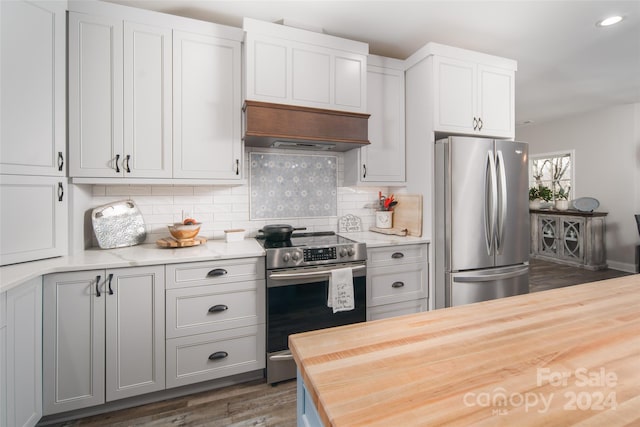 kitchen featuring wooden counters, backsplash, dark hardwood / wood-style flooring, stainless steel appliances, and premium range hood