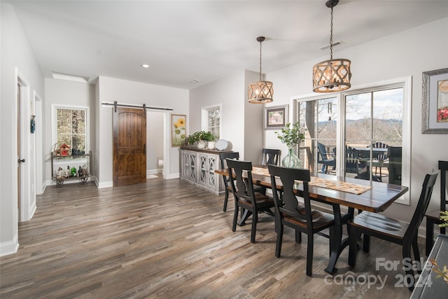 dining room with a wealth of natural light, a barn door, and dark hardwood / wood-style floors