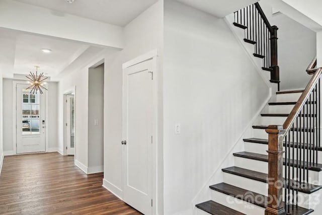 stairway featuring dark hardwood / wood-style flooring and an inviting chandelier