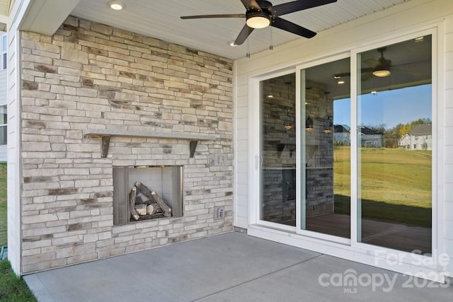 view of patio with ceiling fan and an outdoor stone fireplace