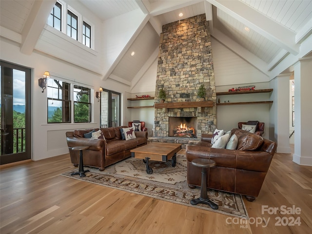 living room featuring beamed ceiling, a fireplace, and light hardwood / wood-style flooring