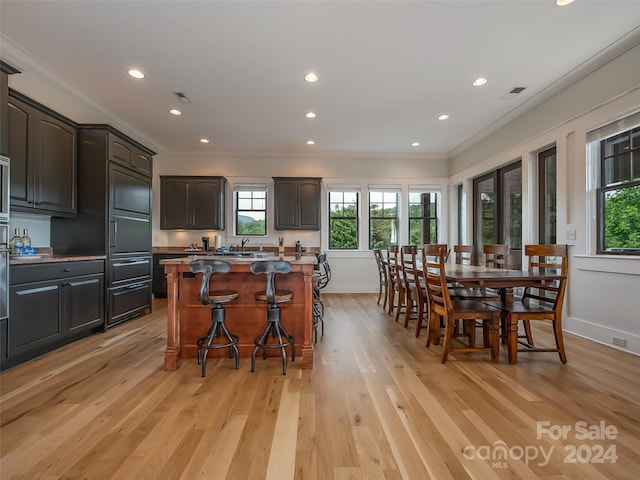 kitchen featuring crown molding, a kitchen island, a breakfast bar, and light hardwood / wood-style flooring