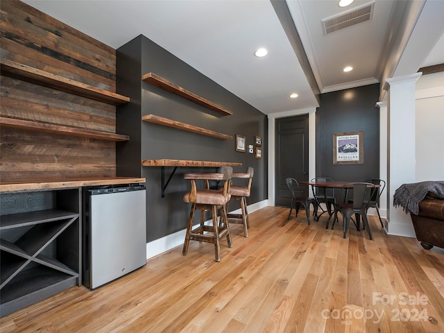 interior space featuring ornamental molding, decorative columns, light wood-type flooring, and refrigerator