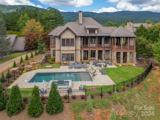 back of house with a yard, a fenced in pool, a mountain view, a patio, and a balcony