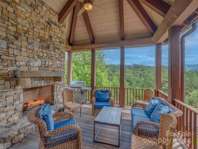 unfurnished sunroom featuring an outdoor stone fireplace, a healthy amount of sunlight, and lofted ceiling with beams