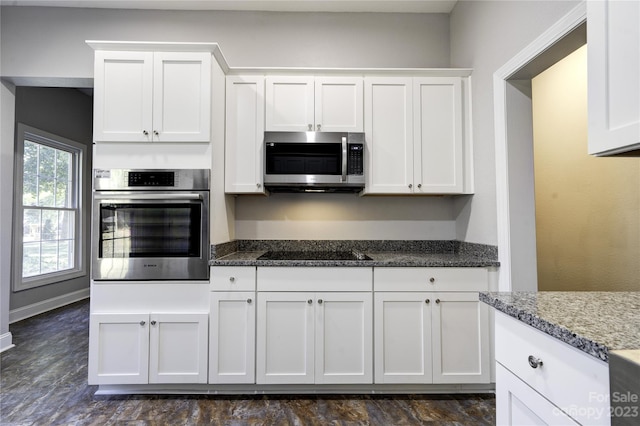 kitchen with stainless steel appliances, dark stone counters, and white cabinets