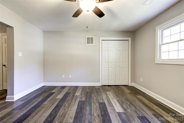 unfurnished bedroom with dark hardwood / wood-style flooring, ceiling fan, and a closet