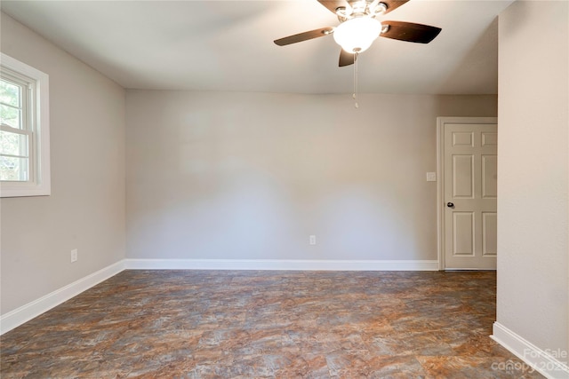 unfurnished room with dark tile floors and ceiling fan