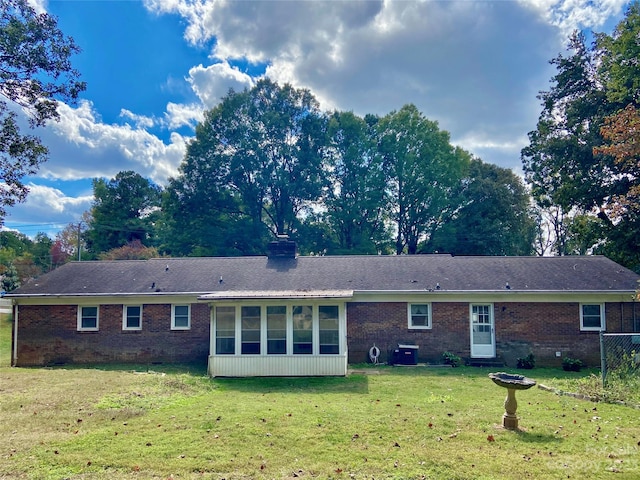 back of property with a sunroom and a yard