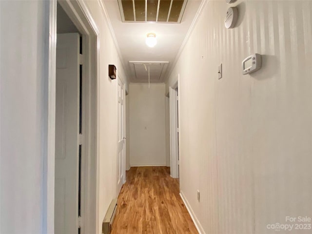 hall with baseboard heating, light wood-type flooring, and ornamental molding