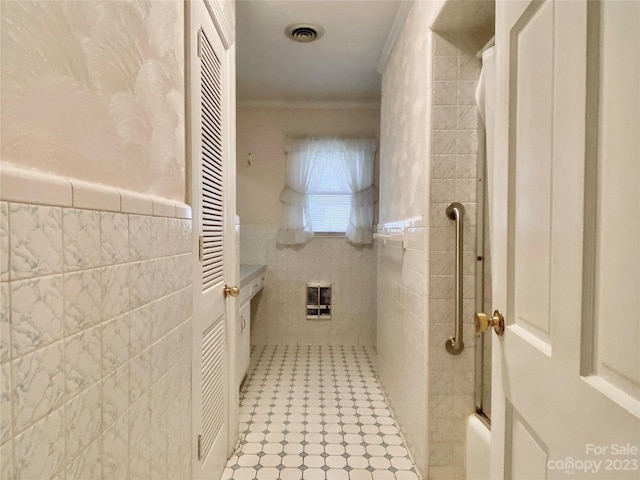 bathroom featuring tile walls, tile floors, enclosed tub / shower combo, vanity, and crown molding