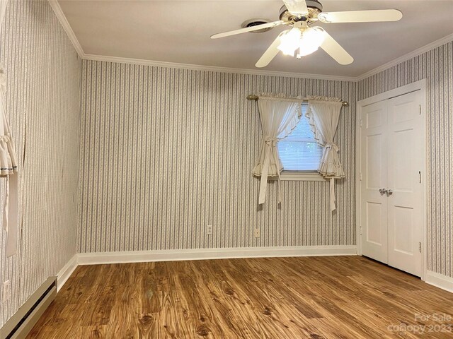 empty room featuring dark hardwood / wood-style flooring, baseboard heating, ceiling fan, and ornamental molding