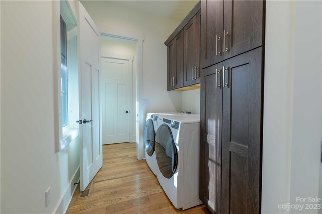 laundry area with cabinets, separate washer and dryer, and light hardwood / wood-style floors