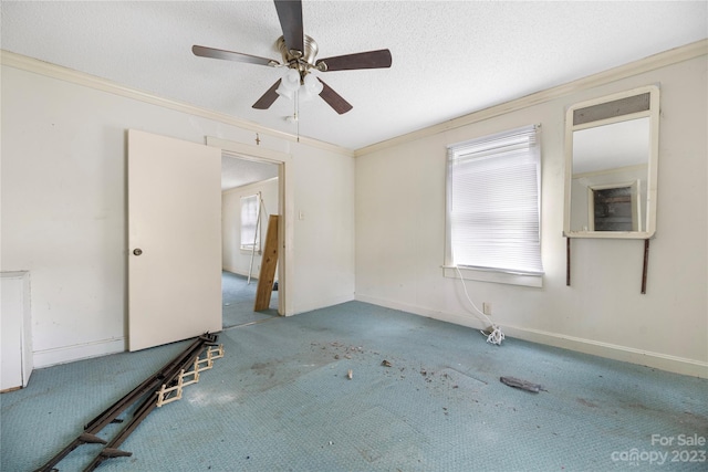 carpeted spare room featuring ceiling fan, crown molding, and a textured ceiling