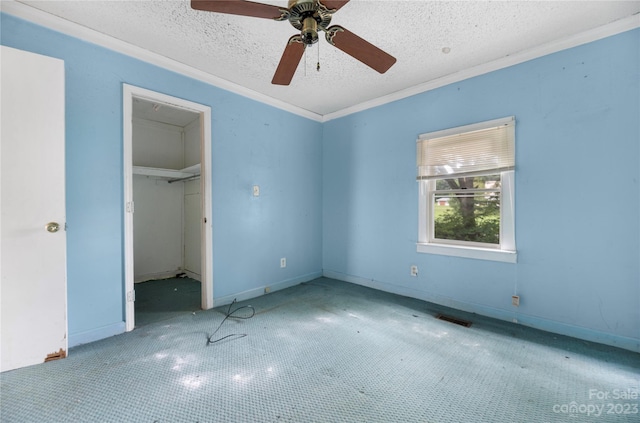 unfurnished bedroom with a spacious closet, a textured ceiling, a closet, and ceiling fan