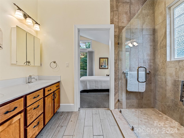 bathroom with vanity, a shower with shower door, and vaulted ceiling