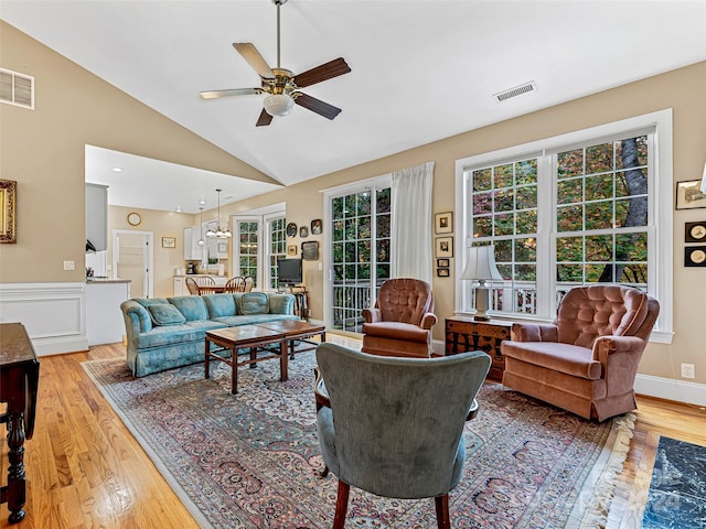 living room with hardwood / wood-style flooring, ceiling fan, and lofted ceiling