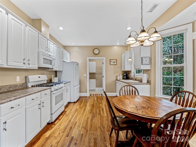 kitchen with white appliances, sink, white cabinets, light hardwood / wood-style floors, and hanging light fixtures