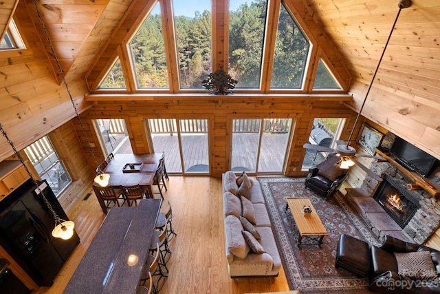 living room with wooden ceiling, light hardwood / wood-style flooring, a wealth of natural light, and wooden walls