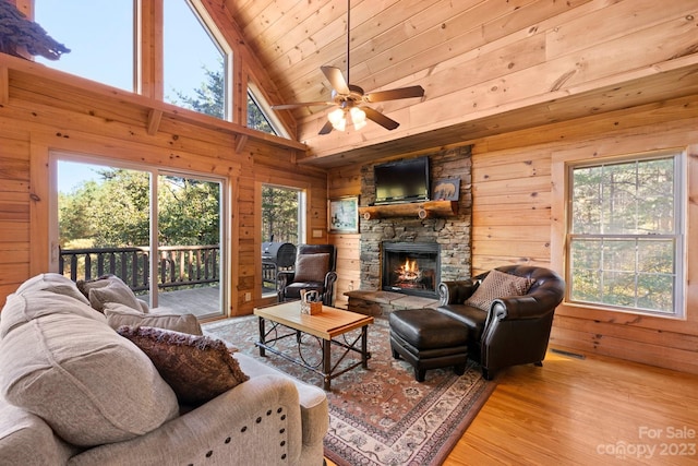 living room with ceiling fan, light wood-type flooring, a fireplace, and a healthy amount of sunlight