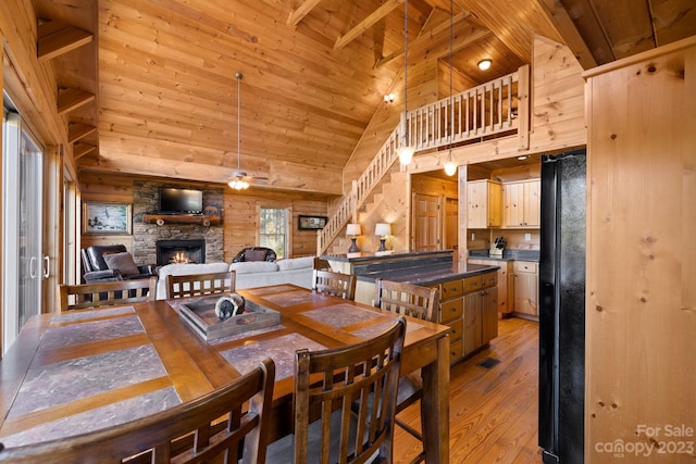 dining room with ceiling fan, a fireplace, high vaulted ceiling, wooden ceiling, and light hardwood / wood-style flooring