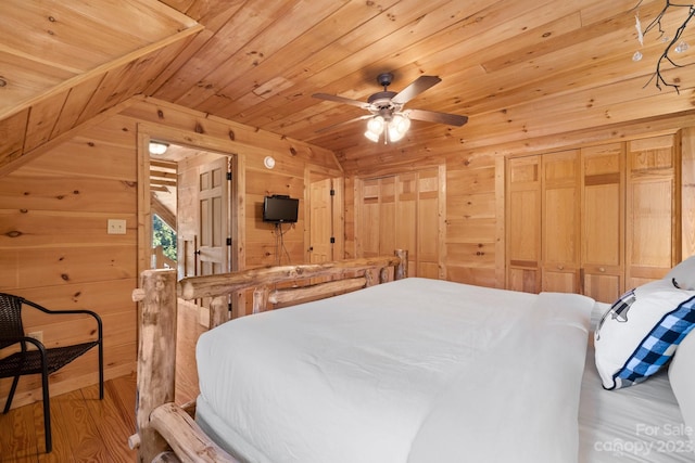 bedroom with wooden walls, ceiling fan, a closet, wooden ceiling, and light hardwood / wood-style flooring