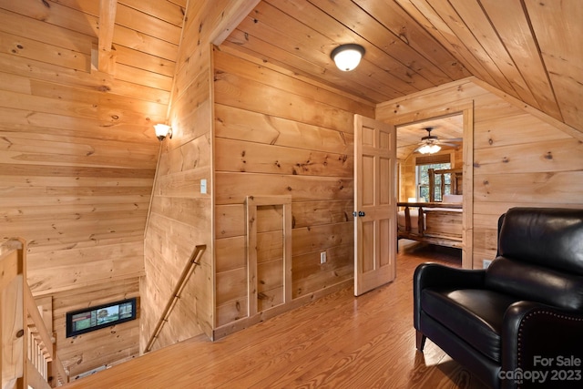 sitting room with light hardwood / wood-style floors, wooden walls, ceiling fan, lofted ceiling, and wood ceiling