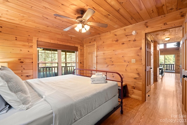 bedroom featuring ceiling fan, light hardwood / wood-style flooring, access to outside, wood walls, and wooden ceiling