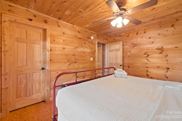 bedroom with wooden walls, ceiling fan, light wood-type flooring, and wooden ceiling