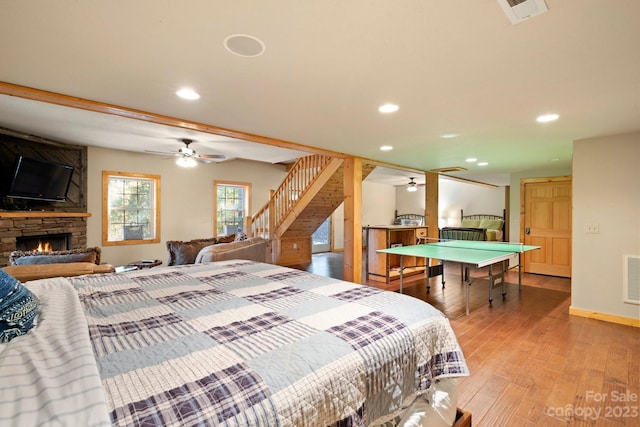 bedroom with ceiling fan, light wood-type flooring, and a fireplace