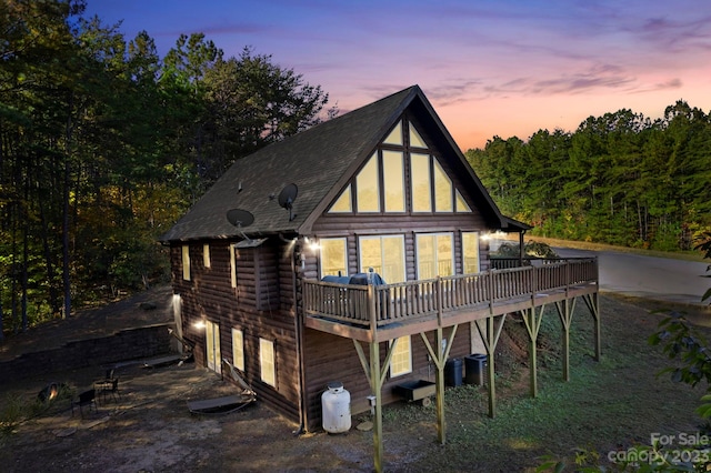 back house at dusk with a wooden deck and central AC