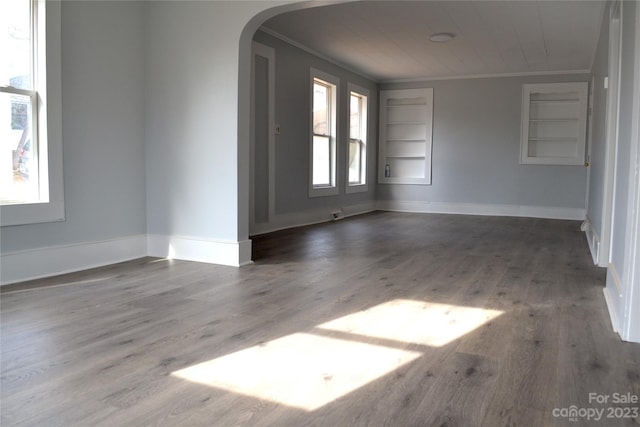 unfurnished room with built in features, ornamental molding, and dark hardwood / wood-style floors