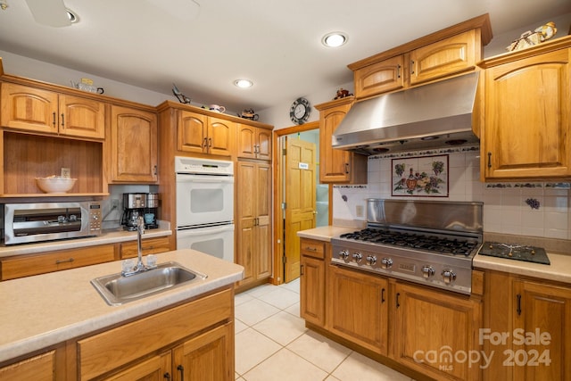 kitchen featuring decorative backsplash, sink, appliances with stainless steel finishes, and range hood