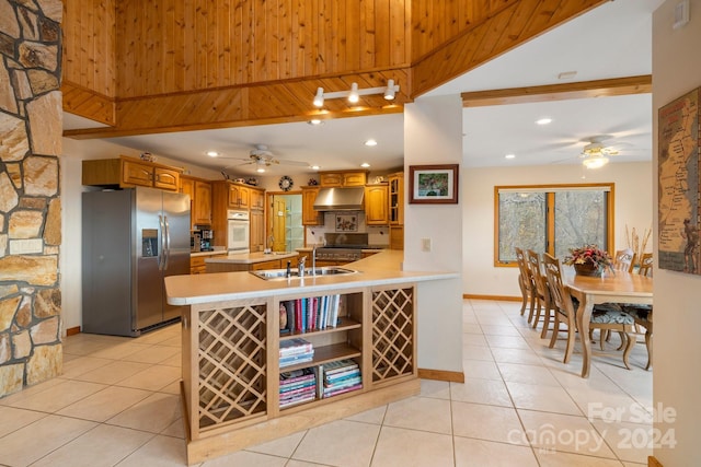 kitchen featuring kitchen peninsula, stainless steel refrigerator with ice dispenser, ceiling fan, sink, and light tile patterned floors