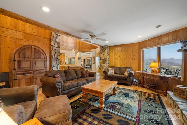 living room featuring ceiling fan, hardwood / wood-style floors, and wooden walls