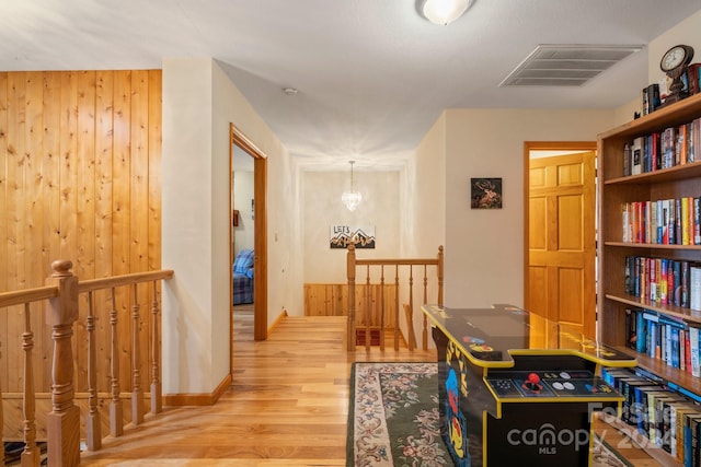 hallway featuring hardwood / wood-style floors, a chandelier, and wooden walls