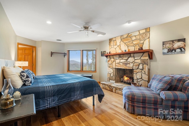 bedroom featuring wood-type flooring, a fireplace, and ceiling fan