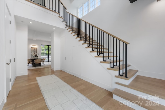 stairs featuring a towering ceiling and hardwood / wood-style floors