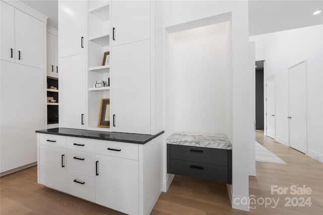 interior space with light hardwood / wood-style floors, white cabinetry, and dark stone countertops